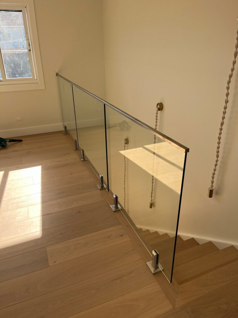 Stair landing with a frameless glass balustrade and timber flooring